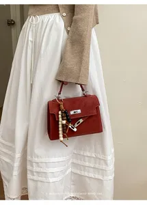 Vue détaillée du sac à main rétro rouge avec serrure en métal et pendentif perlé.
