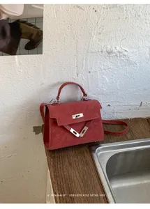 Sac à main rouge en cuir avec fermeture métallique, élégant style rétro chic pour femme.