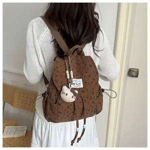 Detaillierte Ansicht des Mini-Kordrucksacks mit niedlichen Schleifenmustern und Plüschanhänger.