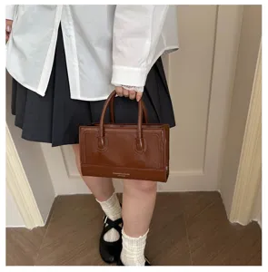 Detail shot of retro brown minimalist leather handbag showcasing exquisite stitching and double handles.