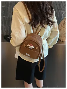 Vue détaillée du mini sac à dos en cuir marron tendance avec joli décor de chiot et bretelles.
