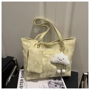 Detail view of the yellow star and moon pattern tote shoulder bag with cute cloud plush charm.