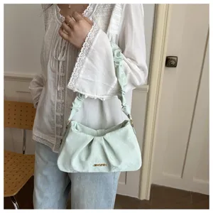 Detailed view of light green ruched underarm bag, showcasing pleated texture and metal hardware.