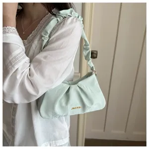 Detailed close-up view of the light green ruched underarm bag, fashionable cloud bag style.