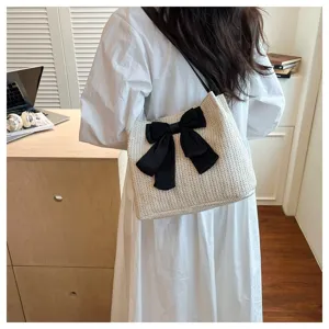 Detailed shot of a stylish straw shoulder bag with a large black bow, elegant summer accessory.