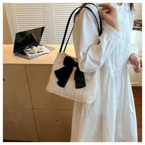 Detail view of the stylish woven straw shoulder bag featuring a chic black bow decoration.