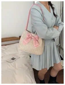 Woven straw shoulder bag detail featuring a stylish pink bow and comfortable pink straps.