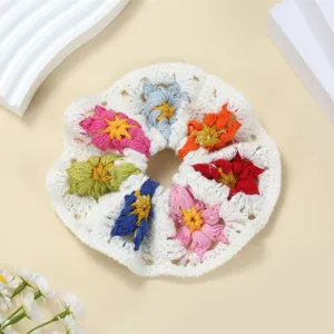 Detail van een handgemaakt gehaakt haarelastiek met kleurrijke bloemmotieven en zachte textuur.