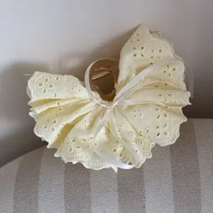 Close-up detail of the sweet light yellow eyelet lace hair claw clip with white ribbon bow.