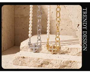 Closeup of pearl and chain spliced necklace with cross pendant in textured stone scene.