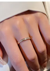 Gros plan d'une bague fine en argent avec des strass carrés portée sur une main.
