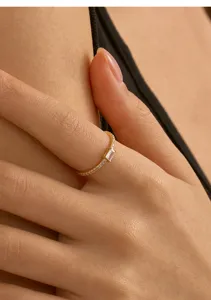 Gros plan détaillé de la bague en argent plaqué or avec zircone taille baguette au doigt.