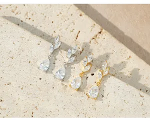 Detailfoto van elegante oorbellen met blaadjes en fonkelende zirkonia in zilver en goud.