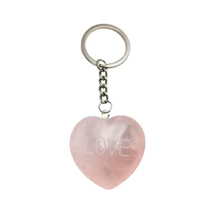 Primer plano de llavero de corazón de cuarzo rosa grabado con texto y anilla.