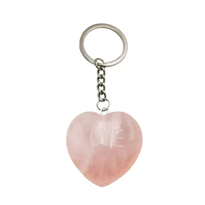 Llavero de corazón de cuarzo rosa natural con texto grabado y detalle de anillo.