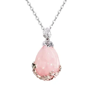 Primo piano dettagliato del ciondolo a goccia in cristallo rosa con montatura floreale in argento.