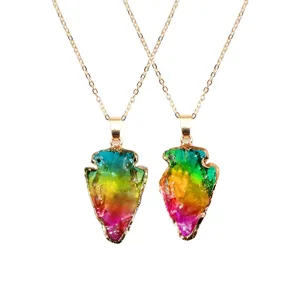 Close-up of colorful crystal arrowhead pendant necklace with gold chain detail, bohemian jewelry.