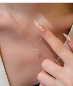 Close-up of a delicate gold-toned cross pendant necklace with sparkling zirconia stones.