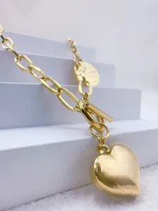 Collana girocollo dorata con catena grossa e ciondolo a cuore per donna su blocco bianco