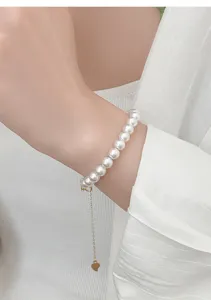 Gros plan de détail d'un élégant bracelet de perles avec pendentif cœur sur un poignet fin.