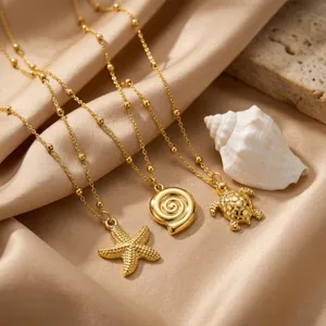 Set di collane in oro sabbia stile oceano con ciondoli stella marina, conchiglia e tartaruga.
