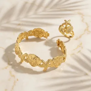 Primo piano dettagliato di bracciale rigido aperto dorato stile mare con anello stella marina.