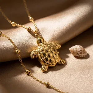 Primo piano dettagliato di una collana con ciondolo a tartaruga d'oro su seta, gioielli.
