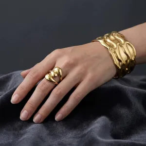 Set bracciale rigido aperto e anello dorato con design organico fluido per donna lusso.