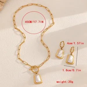 Parure de bijoux en acier titane doré avec pendentif coquillage blanc et boucles.