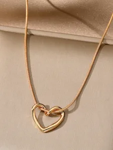 Primo piano dettagliato di una collana girocollo dorata a serpentina con ciondolo a cuore.