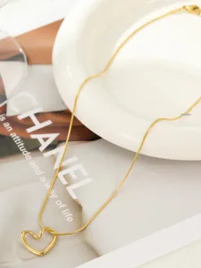 Primo piano dettagliato di una collana minimalista a catena di serpente dorata con ciondolo.