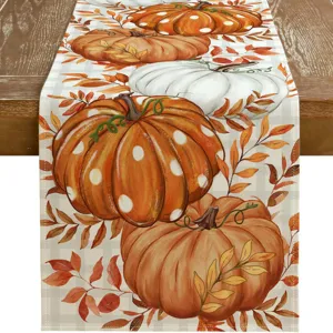 Detailed shot of autumn table runner featuring vibrant pumpkins and fallen leaves pattern.