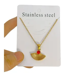 Collier pendentif éventail en acier inoxydable doré avec pierre rouge, bijou élégant et minimaliste.