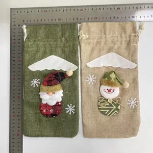 Detalle de funda de botella de vino de arpillera navideña con Papá Noel y muñeco de nieve.