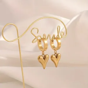 Detailaufnahme von goldenen Ohrringen mit Herzanhänger aus Titanstahl, glänzend.