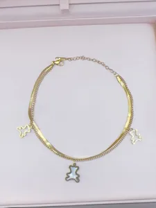 Detailansicht einer doppelten goldenen Kette mit niedlichen Bärenanhängern und Perlmutt-Akzent