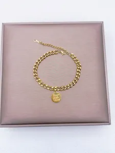 Detailansicht des goldenen Kettenarmbands mit graviertem runden Anhänger und Verschluss.