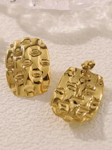 Goldene texturierte Titanstahl Ohrringe im nahen Detail, edler geometrischer Design-Schmuck.