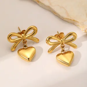 Boucles d'oreilles nœud cœur en acier inoxydable doré gros plan, texture métallique.