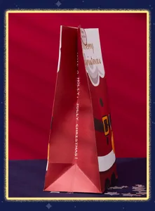 Primer plano detalle de bolsa de regalo de papel navideño con diseño de papá noel.