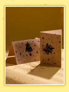Detalle de tarjeta de felicitación navideña plegable con papel artesanal y árbol festivo.