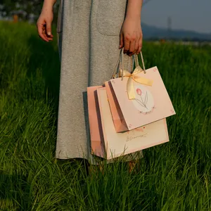 Bolsas de regalo de papel rosa con elegante estampado de tulipanes y lazo, ideales para fiestas.