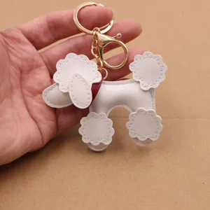 Detailed view of a white leather poodle dog keychain charm with gold metal hardware and clasp.