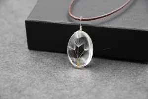 Handgemaakte, transparante ovale hars ketting met natuurlijke paardenbloemzaden van dichtbij.