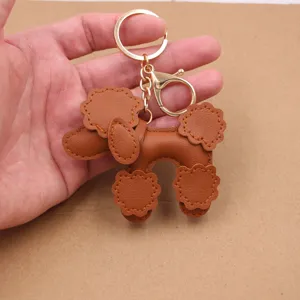 Brown leather poodle keychain close-up, cute puppy pendant for bags and car keys display.