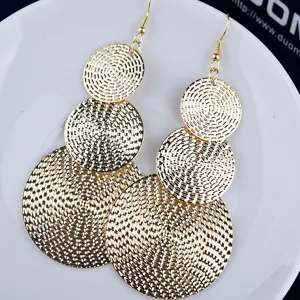 Boucles d'oreilles pendantes à disques dorés multicouches, gros plan bijou vintage.