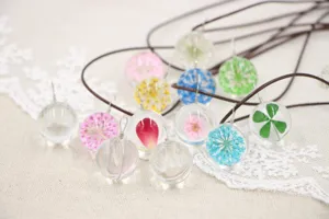 Handmade dried flower glass ball necklace detail, clear plant specimen pendant jewelry.