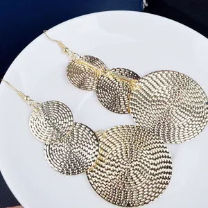 Vue détaillée des boucles d'oreilles pendantes dorées à disques multiples vintage.