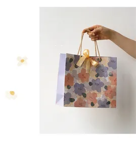 Elegante bolsa de regalo de papel floral con lazo para detalles de embalaje de fiesta.