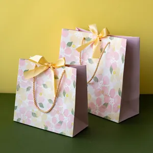 Bolsa de regalo de papel floral rosa con lazo amarillo y asas para fiestas de cumpleaños y eventos